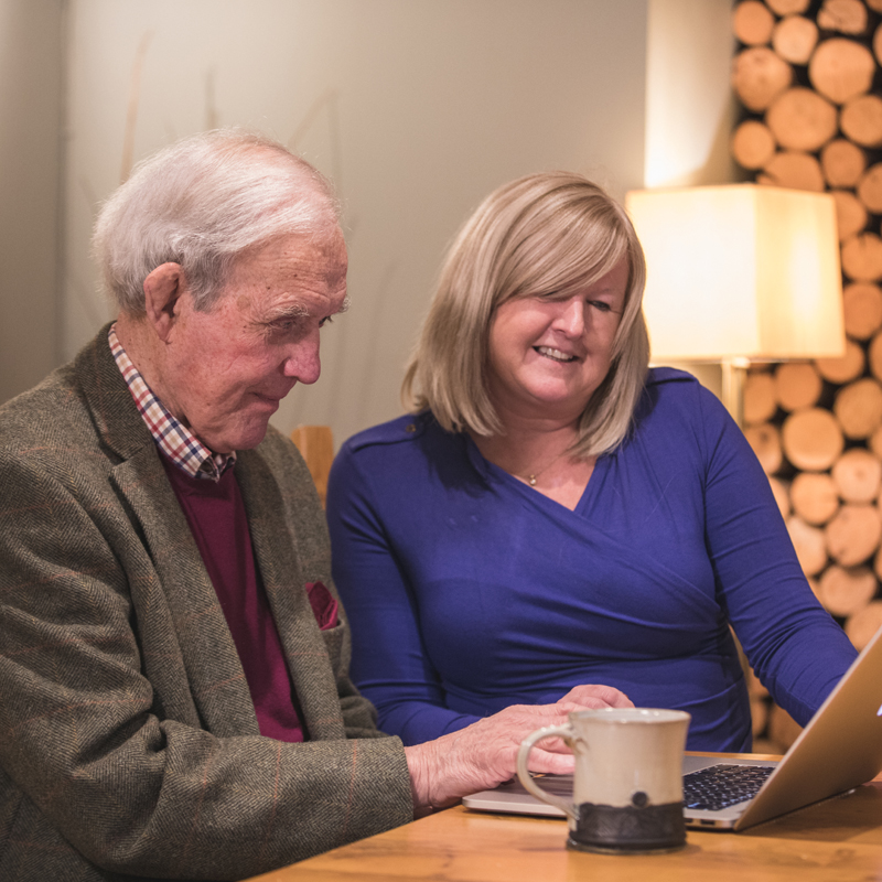 live-in-care-jobs carer and client looking at the care plan on the internet